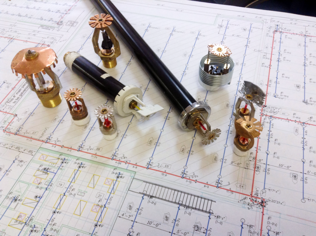Sprinkler heads laid across blueprints.